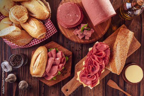 Mortadella sandwich on a wood cutting board with bread, butter and spices - Top view photo