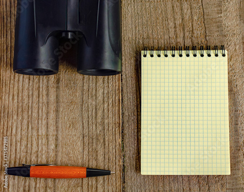Yellow notebook, binoculars and pen. Birdwatching.