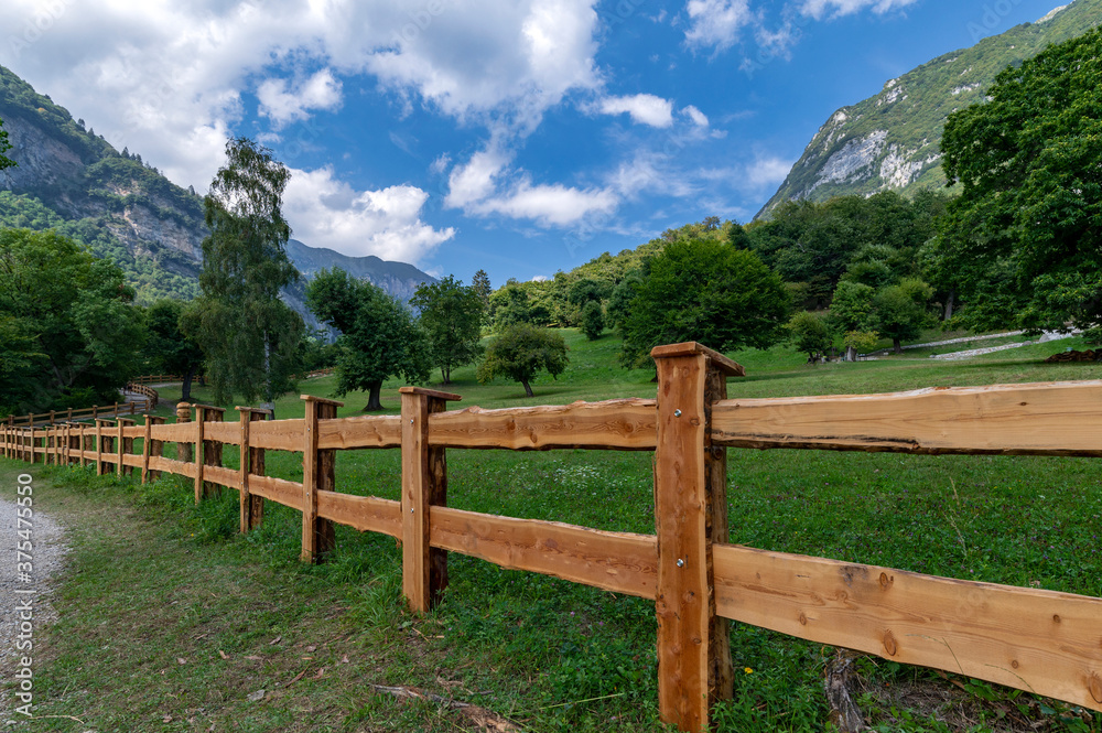 Wooden fence with summer landscape in the mountains, clouds, blue sky near lake tenno, wine route, near Lake Garda, Riva del Garda, Trentino Alto Adige, Trento, Italy