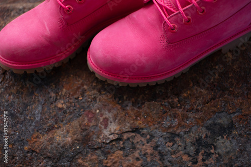 Autumn Fashion Concept. Pink leather women boots on brown iron background top view copy space. Autumn shoes.