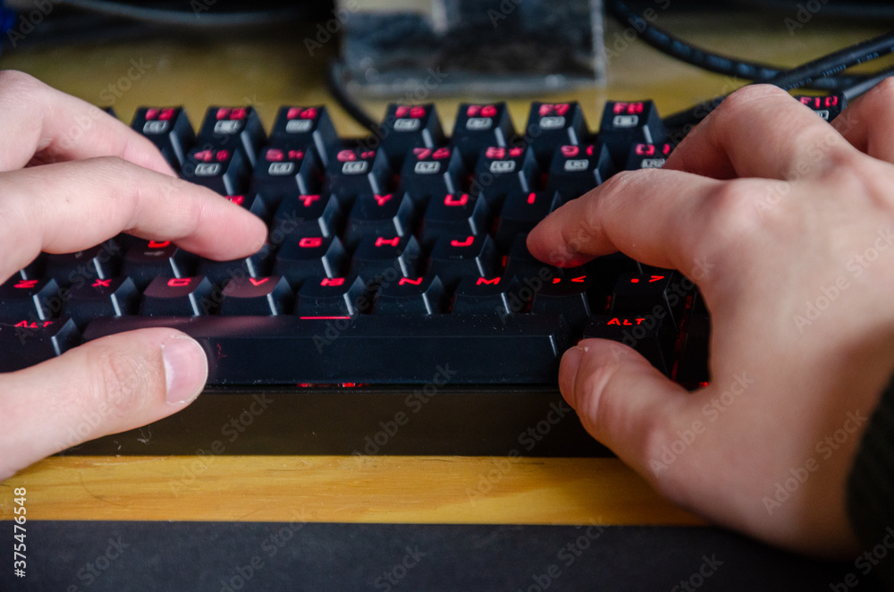 close up on male hands working on a keyboard with red lights close up on male hands working on a keyboard with red lights