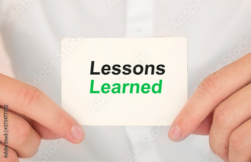 Man's hands take a card with words Lessons learned, finance and business concept.