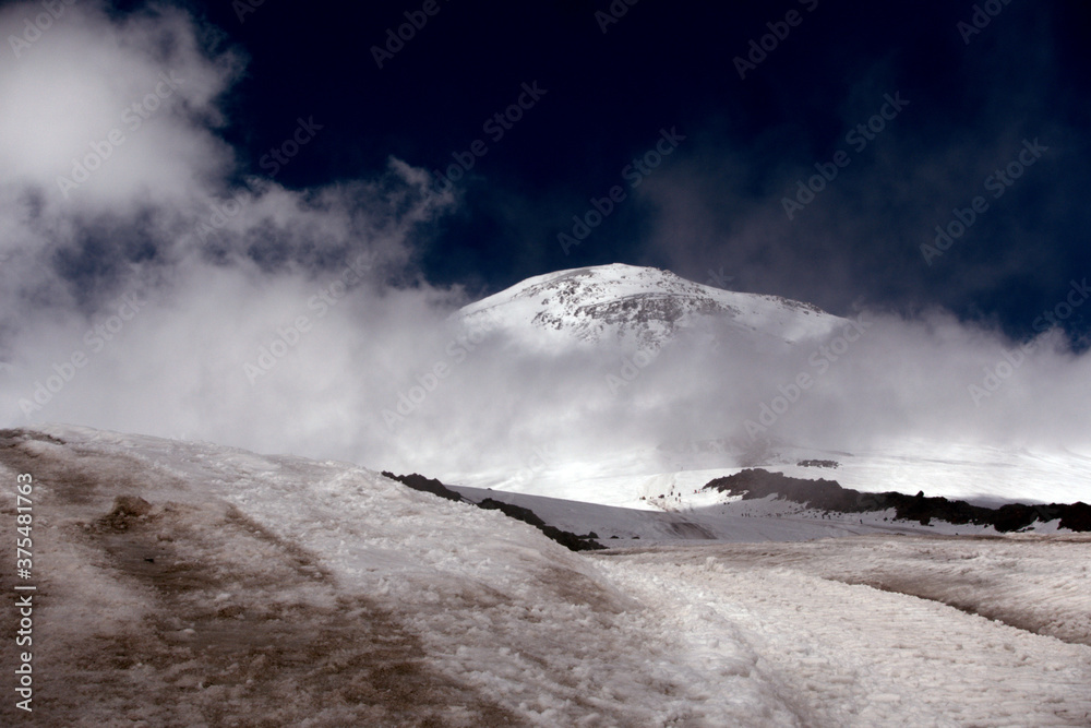 Climbing Elbrus. Snow-capped mountain peaks and figures of climbers in the foreground. Mountains covered with snow.