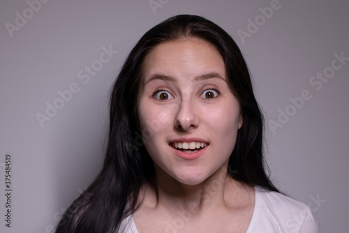 Young suprised brunette woman, isolated on gray background. happy girl actress portrait. The human emotions, facial expression concept