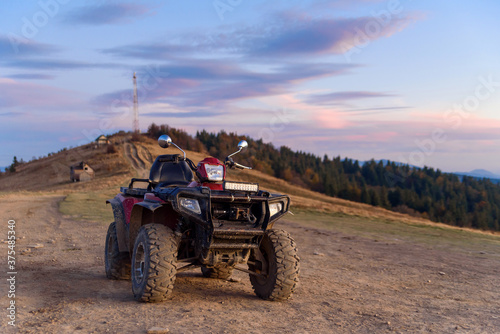 ATV on the mountain top at summer sunset background. Travel and extreme tourism concept.