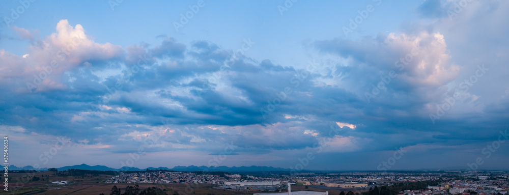 Panoramic photo of a drone of clouds with rain on the right side, in the background the mountains of the sea of Paraná and below Pinhais, in the Metropolitan Region of Curitiba, Paraná