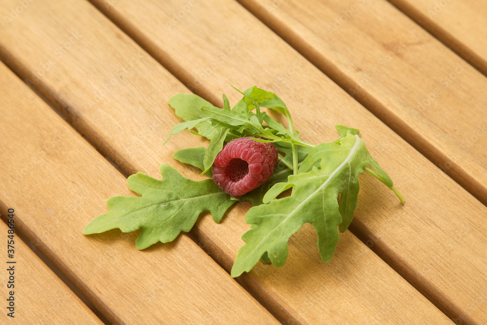 fresh arugula and raspberries on a wooden table fresh arugula and raspberries on a wooden table