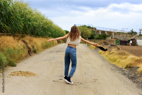 Chica de espalda con los brazos abiertos en campos de trigo.  photo
