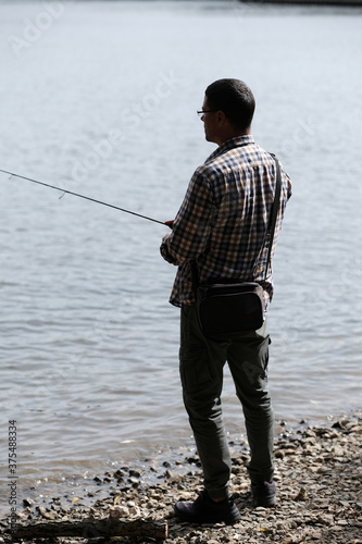 Fisherman holding spinning rod in hands and catching fish. Concept of sport, hobby and leisure time in the city.