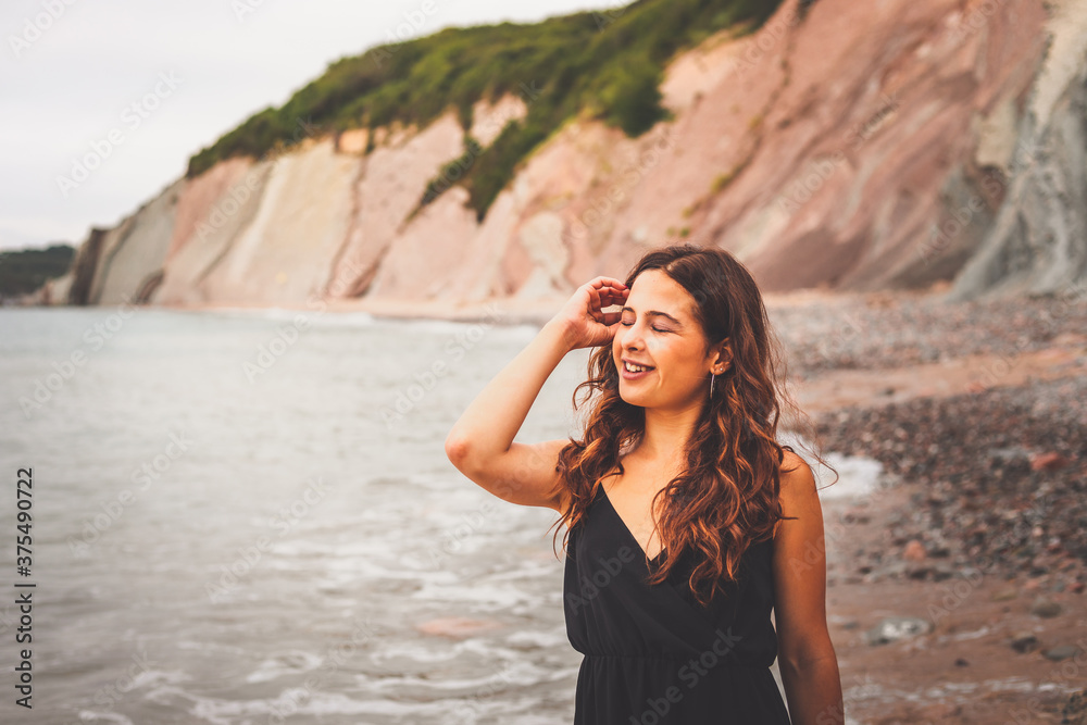 Nice girl with a black dress in a rocky cove in the basque coast. Nice girl with a black dress in a rocky cove in the basque coast.