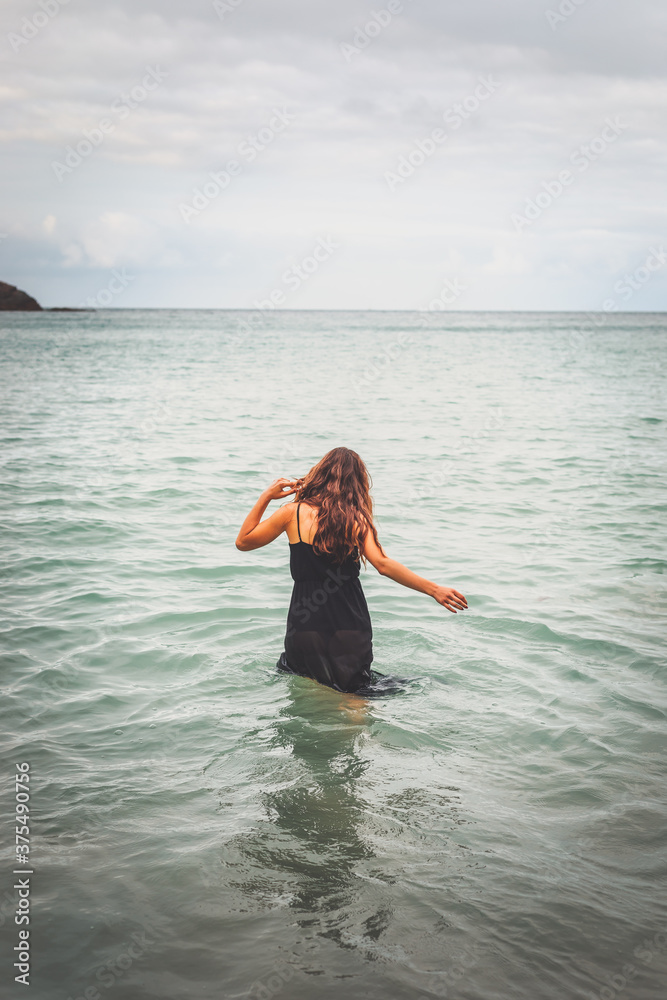 Girl with a black dress in the sea at the basque coast.