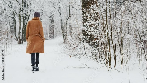 Active woman in classic coat walks through snowy park photo