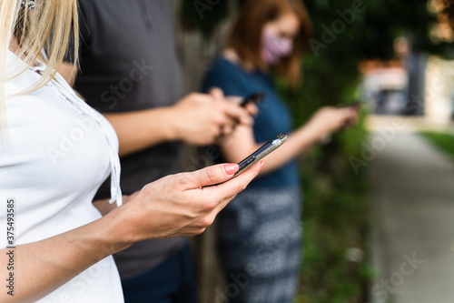Close up on hands of unknown caucasian men using mobile phone - Modern communication online texting social network messaging - Midsection men and woman holding mobile phones outdoor - social distance