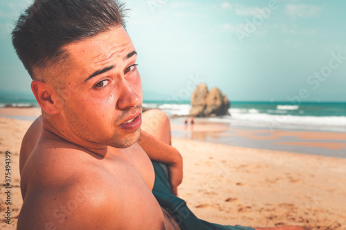 Young caucasian man posing at a beach in a summer morning in the basque coast.
