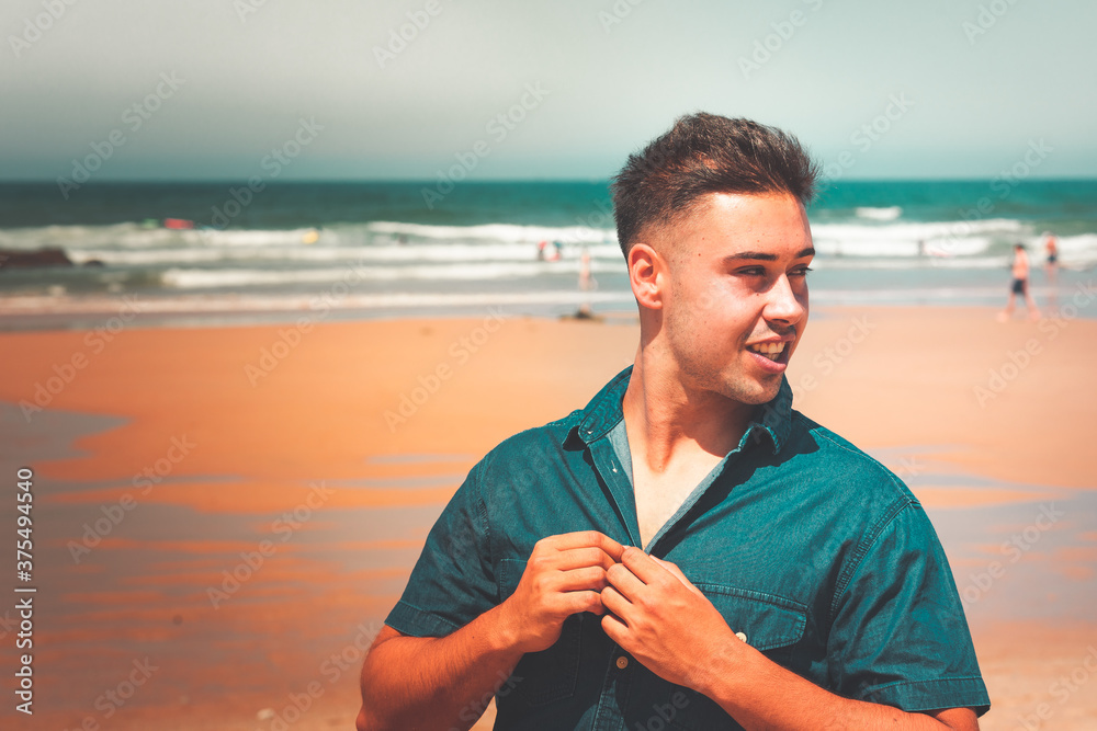 Young caucasian man posing at a beach in a summer morning in the basque coast.