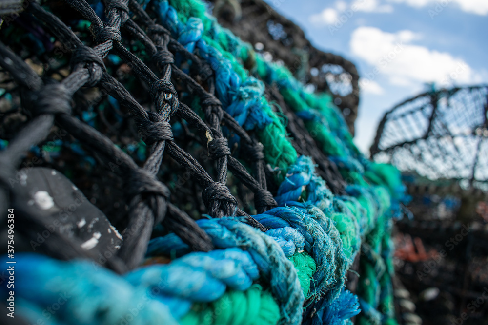 Crab trap cages in piles, blue rope closeup, dirty cages used to catch large numbers of crabs in Mudeford Quay UK, close shot with selective focus of lobster pots, outside of the cages