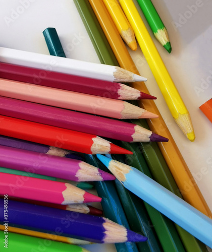 Heap of colored pencils on the white table background