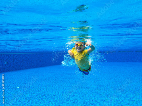 Child underwater in swimming pool. Kids swim.