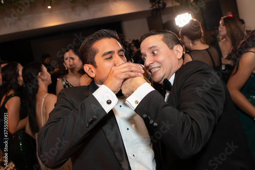 Latino Best Man giving the groom a drink in celebration