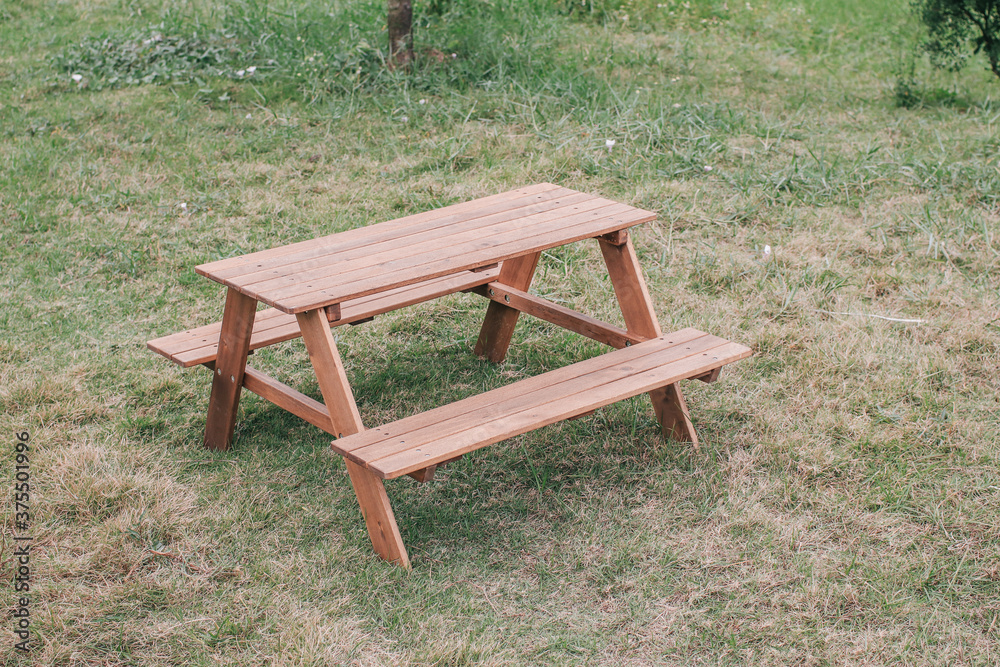 Outdoor picnic wooden table in park with green grass field enjoying sunny weekend summer day outdoor. Outdoor picnic wooden table in park with green grass field enjoying sunny weekend summer day outdoor.