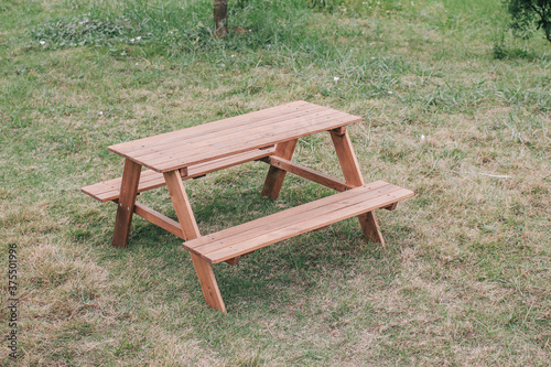 Outdoor picnic wooden table in park with green grass field enjoying sunny weekend summer day outdoor.