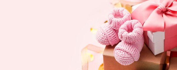 Beautiful composition with pink baby booties and gift box on pink background. Concept of baby shower party, first birthday holiday card, copy space, banner