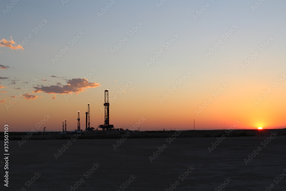 Rare image of the West Texas desert landscape during sunset with 5 drilling rigs in the background. Rare image of the West Texas desert landscape during sunset with 5 drilling rigs in the background.