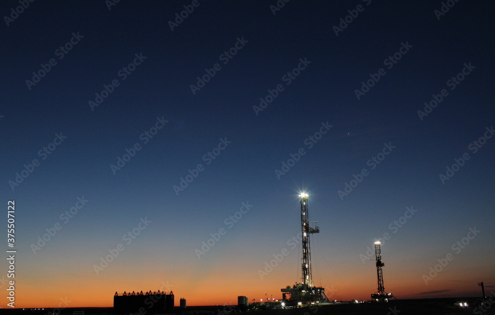 Beautiful sunrise with 2 drilling rigs in the background; West Texas Permian Basin Drilling. If zoomed in, Venus is visible over the rigs. Beautiful sunrise with 2 drilling rigs in the background; West Texas Permian Basin Drilling. If zoomed in, Venus is visible over the rigs.