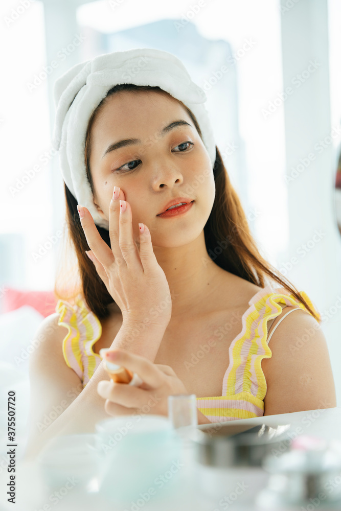 Asian dark hair woman using cosmetic facial skin care at mirror. Asian dark hair woman using cosmetic facial skin care at mirror.