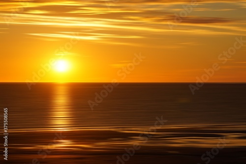 Awesome sunrise on the calm sea in orange gold yellow brown tones and soft clouds fine art photography © Christiane