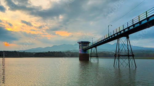 The reservoir landscape when sunset and beautiful clouds, the middle bridge of the reservoir, the silhouette of muria mountains and cloudy skies