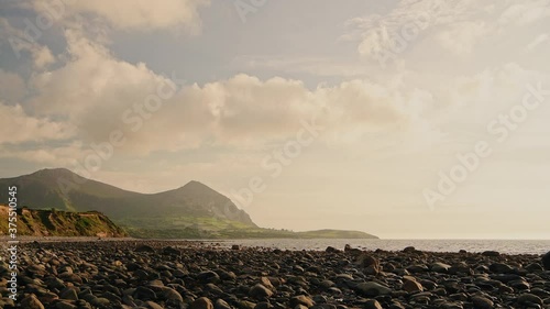 Stunning sunset at rocky coast of Wales with Yr Eifl mountain in background photo