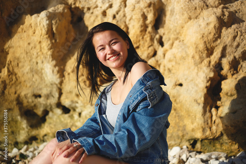 portrait of a woman in a denim jacket on a background of yellow rock