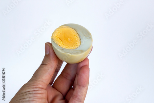 Hand is holding bruised and boiled,unhealthy egg on white