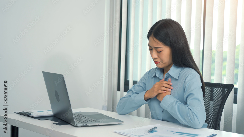 Young asian woman is sitting at work and has chest pain due to stress. Young asian woman is sitting at work and has chest pain due to stress.