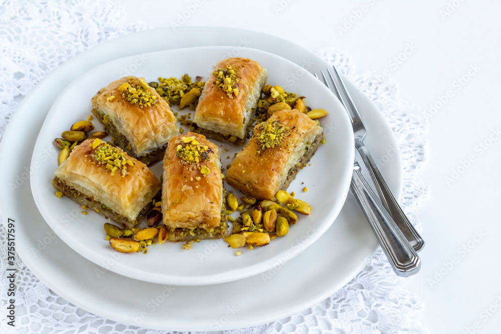 Traditional Turkish Pastry Dessert Baklava special designed on plate with pistachio nuts and cutlery set Traditional Turkish Pastry Dessert Baklava special designed on plate with pistachio nuts and cutlery set