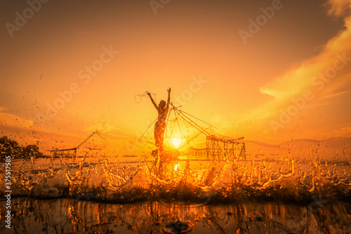 Nakorn Si Thammarat, Thailand-August 16, 2020 : Silhouette Fisherman Fishing Nets on the boat at sunrise in Thailand photo