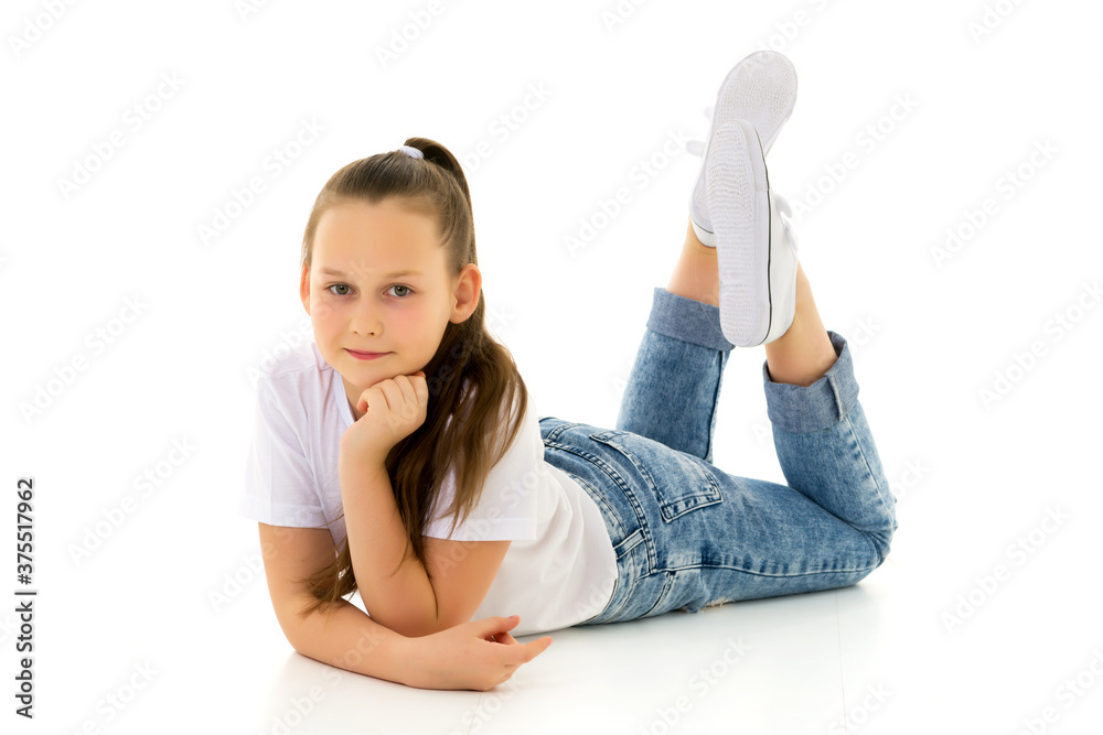 Little girl lies on the floor.Studio photo shoot on a white back Little girl lies on the floor.Studio photo shoot on a white back