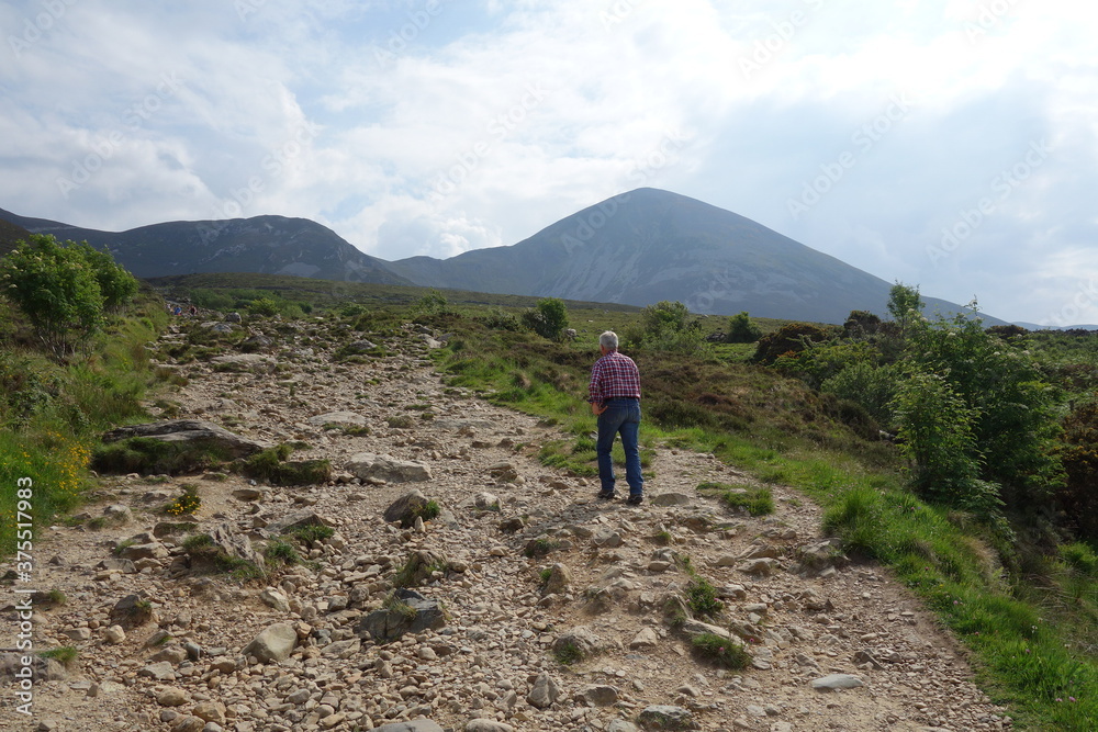 Fototapeta premium Einsamer Wanderer wandert steinigen Weg nach oben. Sabdy rocky path.