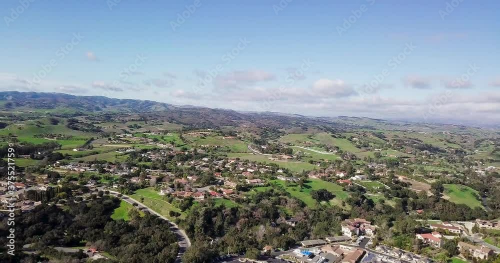 Country side houses of german town surrounded by lush green mountains under a blue sky with clouds, camera move and rotate left