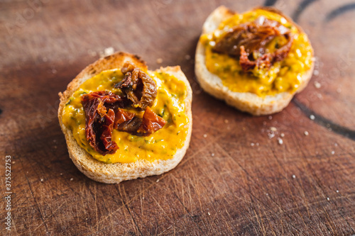 simple food ingredients, bread slices with sweet potoato and kale dip topped with sundried tomatoes