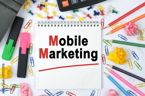 On the table is a calculator, diary, markers, pencils and a notebook with the inscription - Mobile Marketing