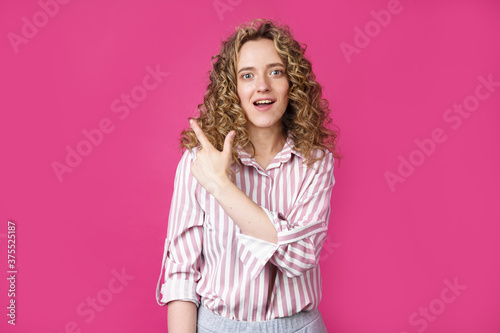 Young beautiful woman shows her finger to the left.