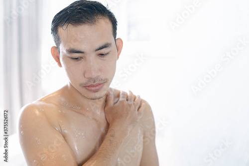 Closeup young man washing hair with with shampoo in the bathroom, vintage tone, selective focus