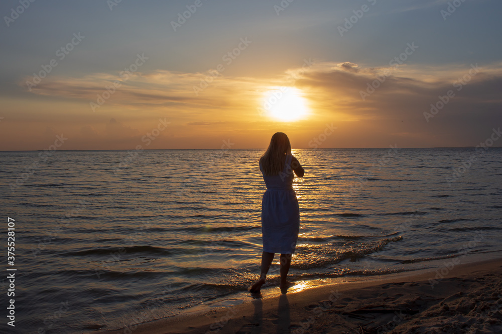 girl in a dress by the sea at sunset