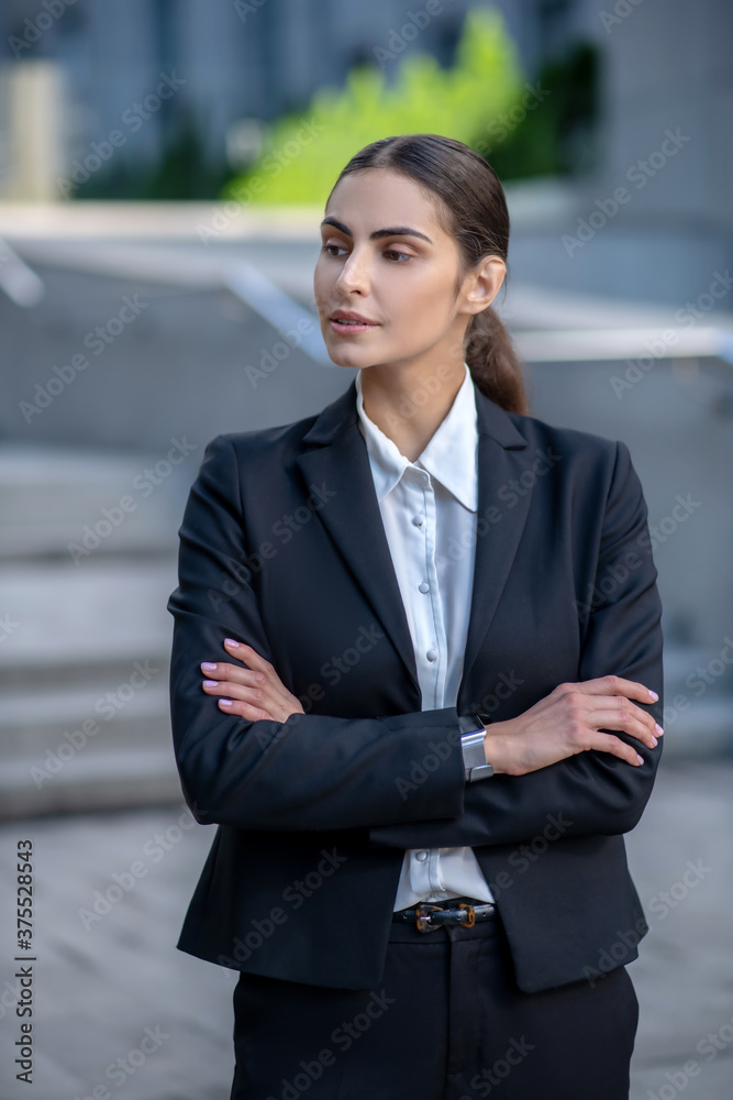 Elegant woman in a black suit standing with arms folded Elegant woman in a black suit standing with arms folded
