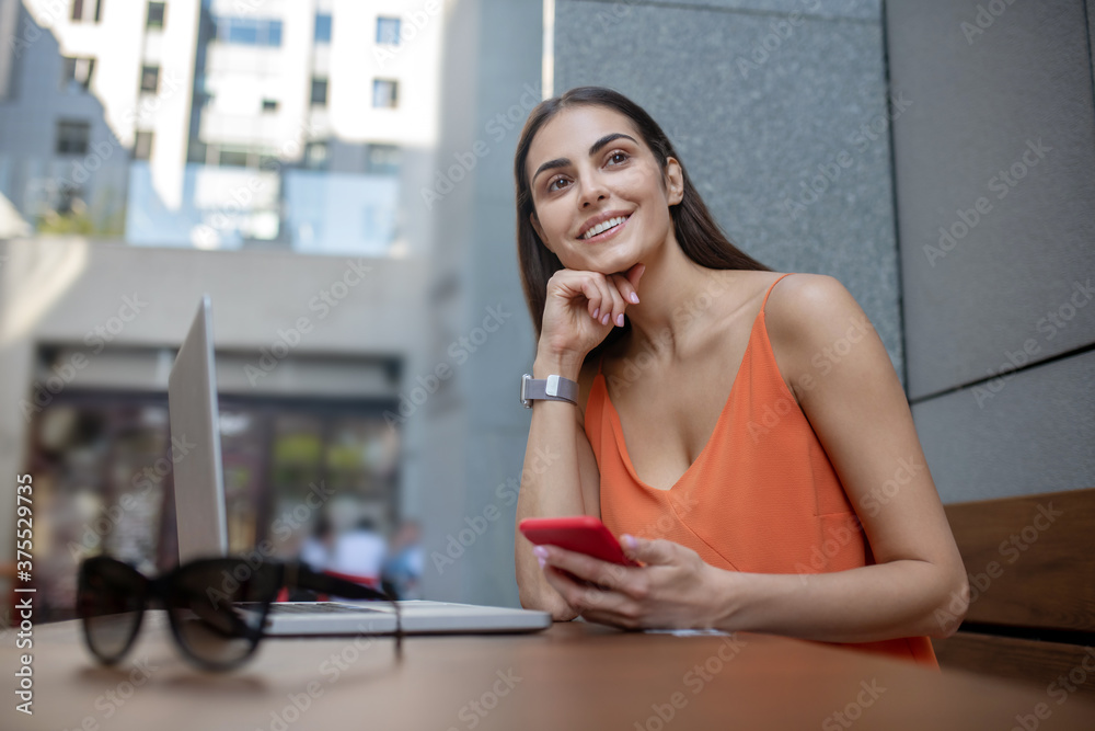 Dark-haired pretty woman with a smartphone looking anticipated Dark-haired pretty woman with a smartphone looking anticipated