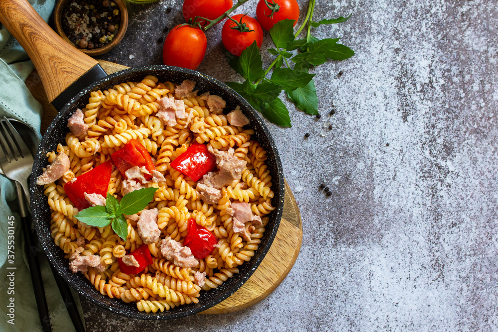 Healthy lunch. Fusilli pasta with canned tuna, grilled red peppers and tomatoes in frying pan on a stone countertop. Top view flat lay background. Copy space. Healthy lunch. Fusilli pasta with canned tuna, grilled red peppers and tomatoes in frying pan on a stone countertop. Top view flat lay background. Copy space.