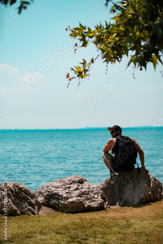 Fit Man sitting on a rock in front of a blue lake