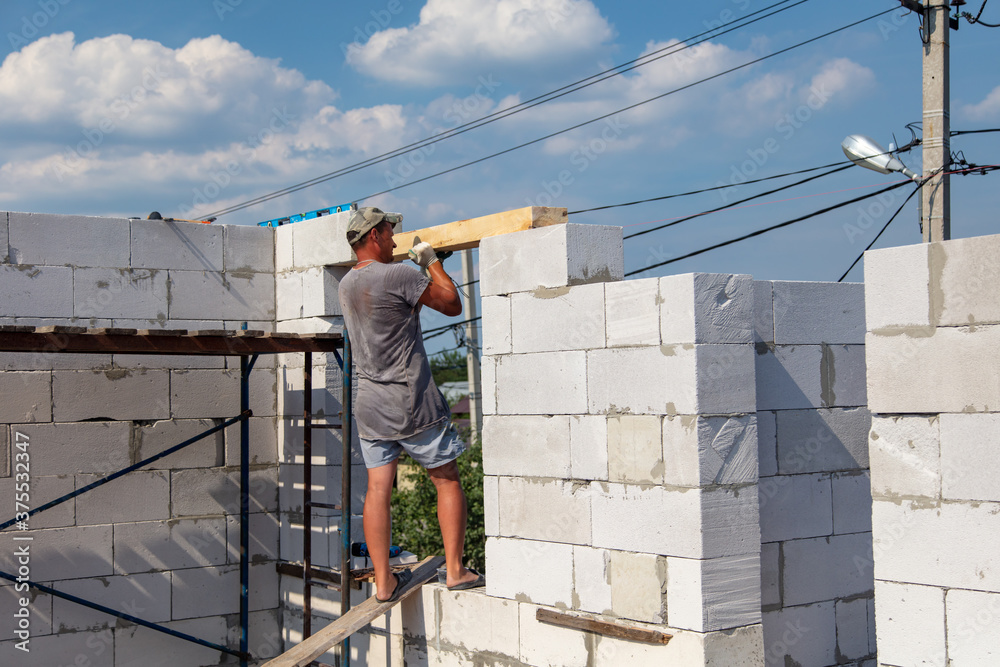 A worker builds the walls of a house from aerated concrete bricks. A worker builds the walls of a house from aerated concrete bricks.